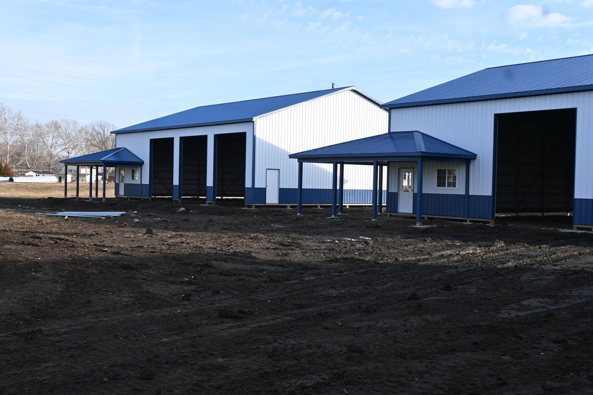 A white post-frame building with blue wainscot built by Hershberger's Construction