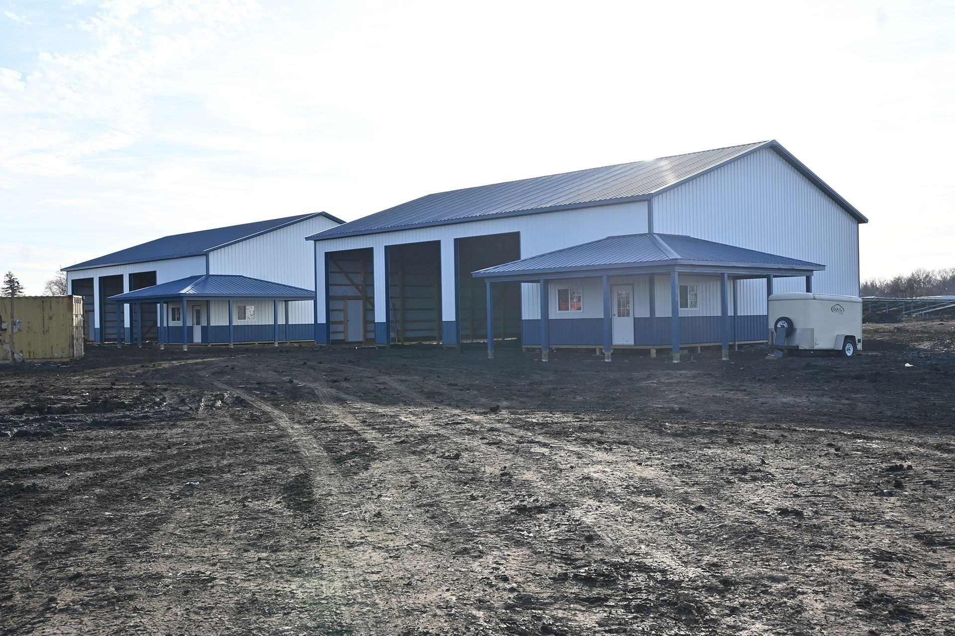 Post-frame building with blue trim and a wrap-around porch
